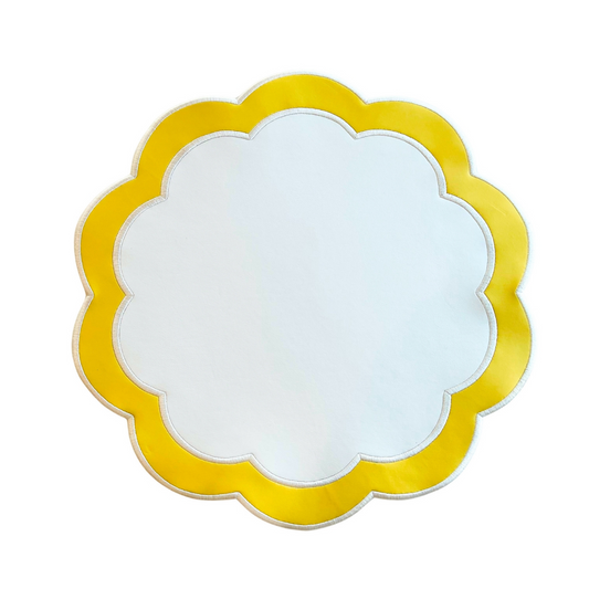 A round placemat with white and yellow faux leather, featuring a floral-like design around the edge, displayed on a white background.