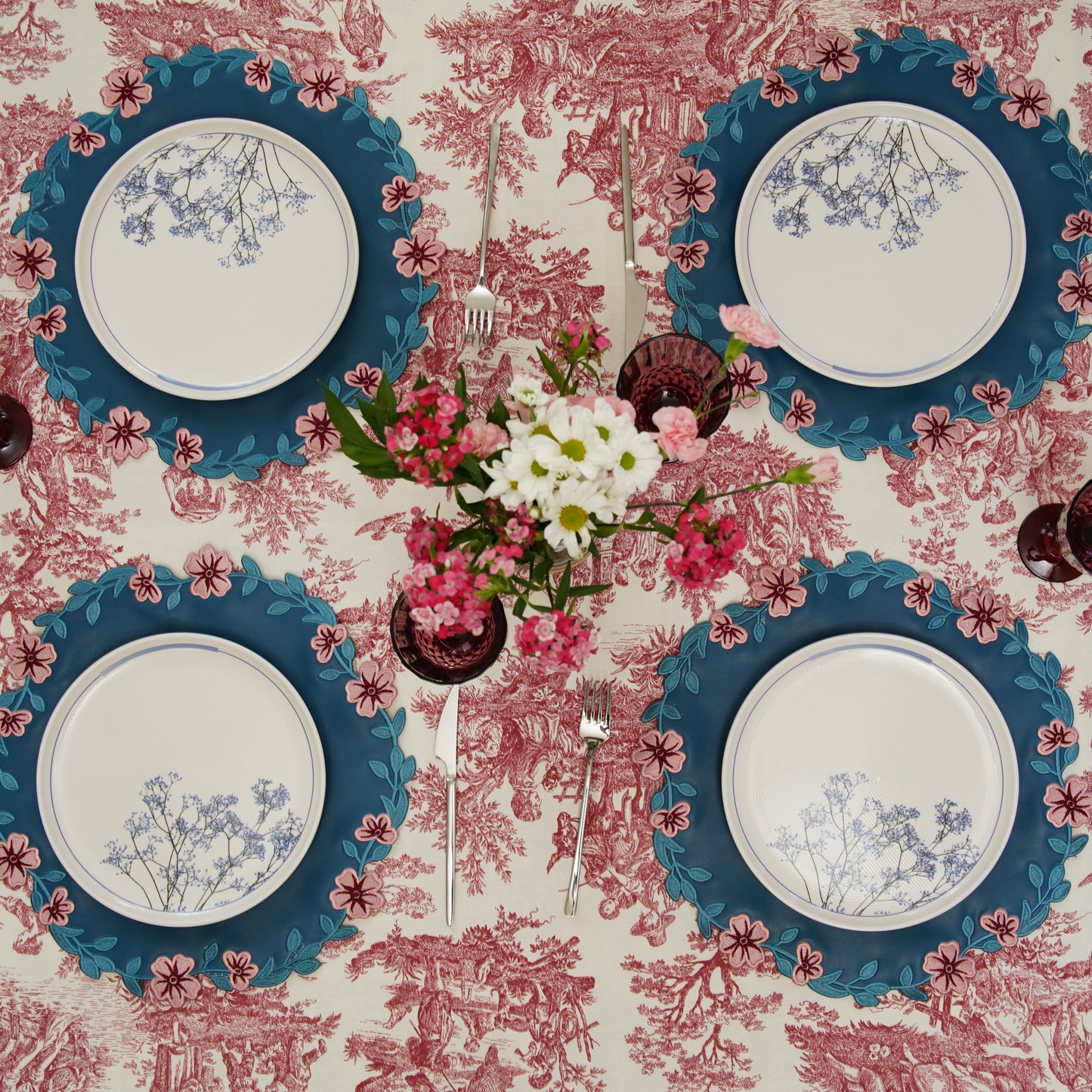 Table setting with blue-rimmed plates on a floral tablecloth