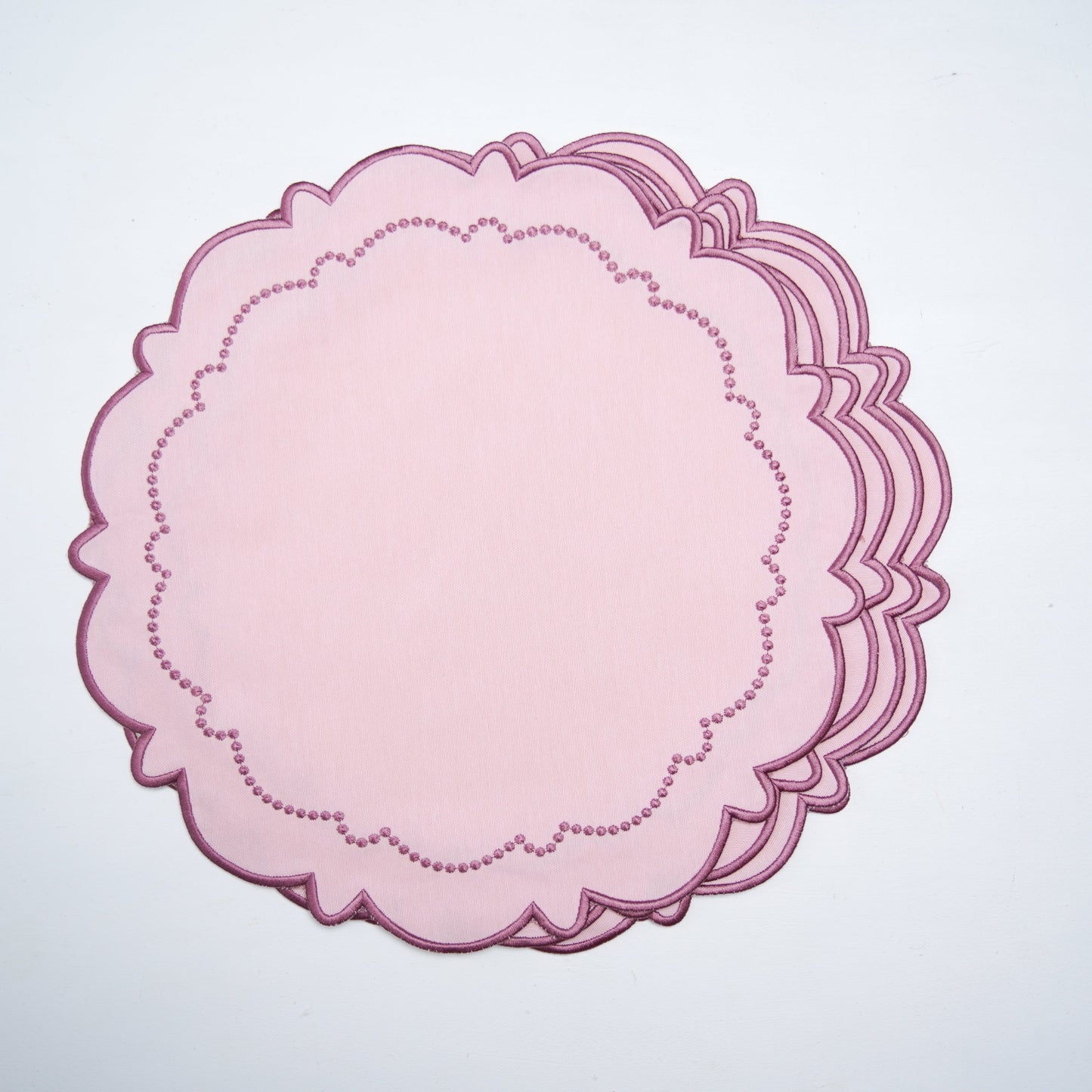 Pink scalloped paper cutout on a white background