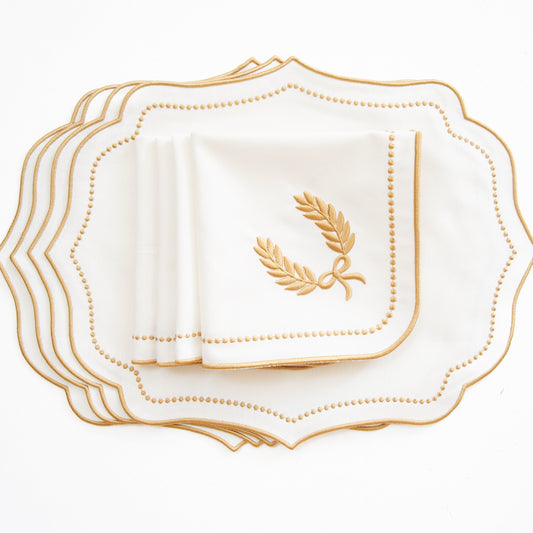 Set of white plates with gold rim and decorative emblem on a white background