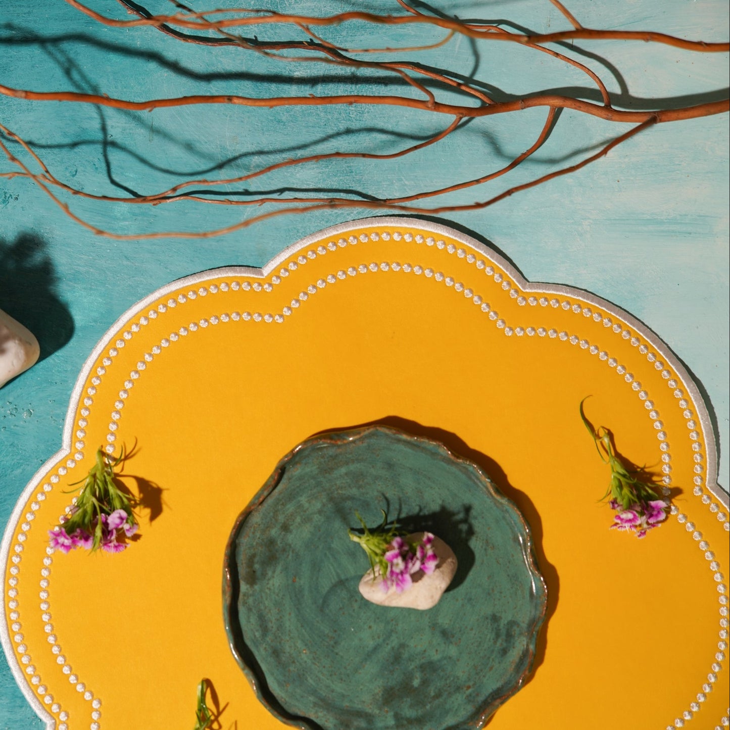 Decorative plate with a central green dish, flowers, and a yellow rim on a blue background.