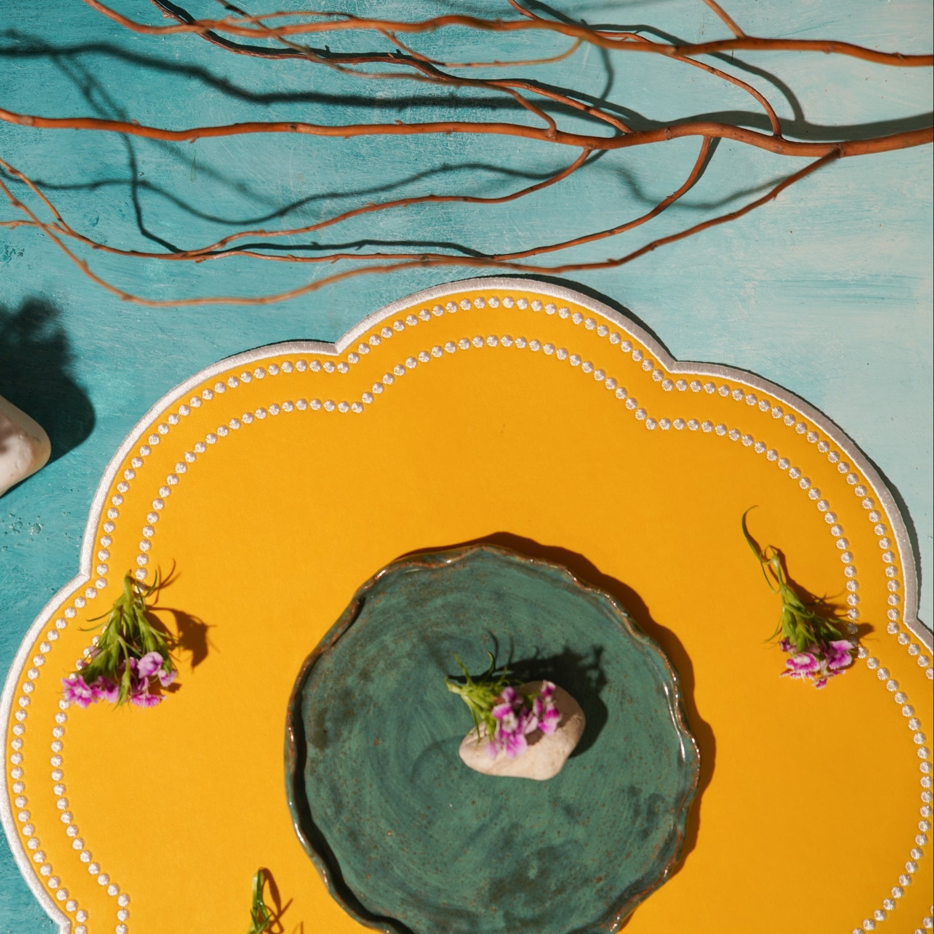 Decorative plate with a central green dish, flowers, and a yellow rim on a blue background.