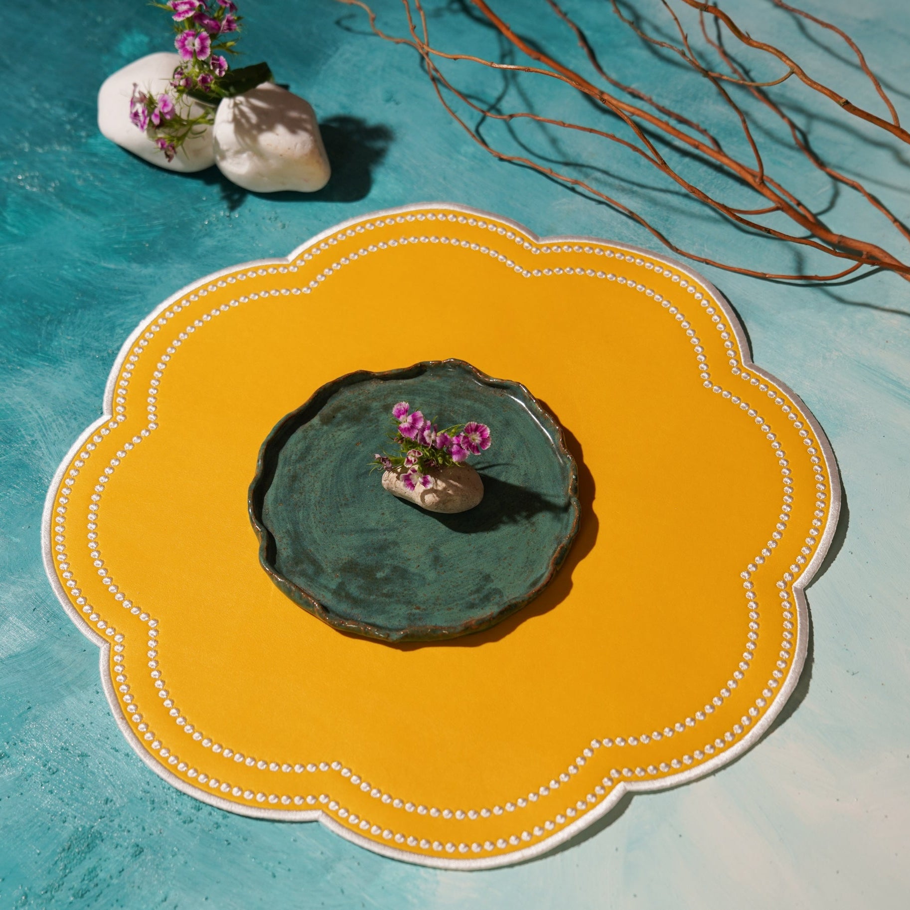Decorative yellow plate with a green ceramic dish and small plant on a textured blue surface.