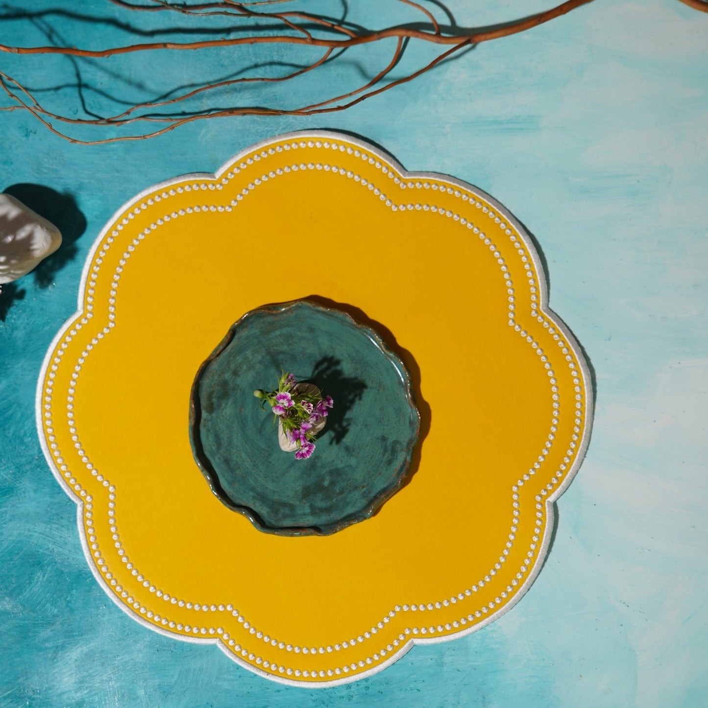 A yellow faux leather placemat with a decorative pattern, displayed on a table with a blue backdrop.