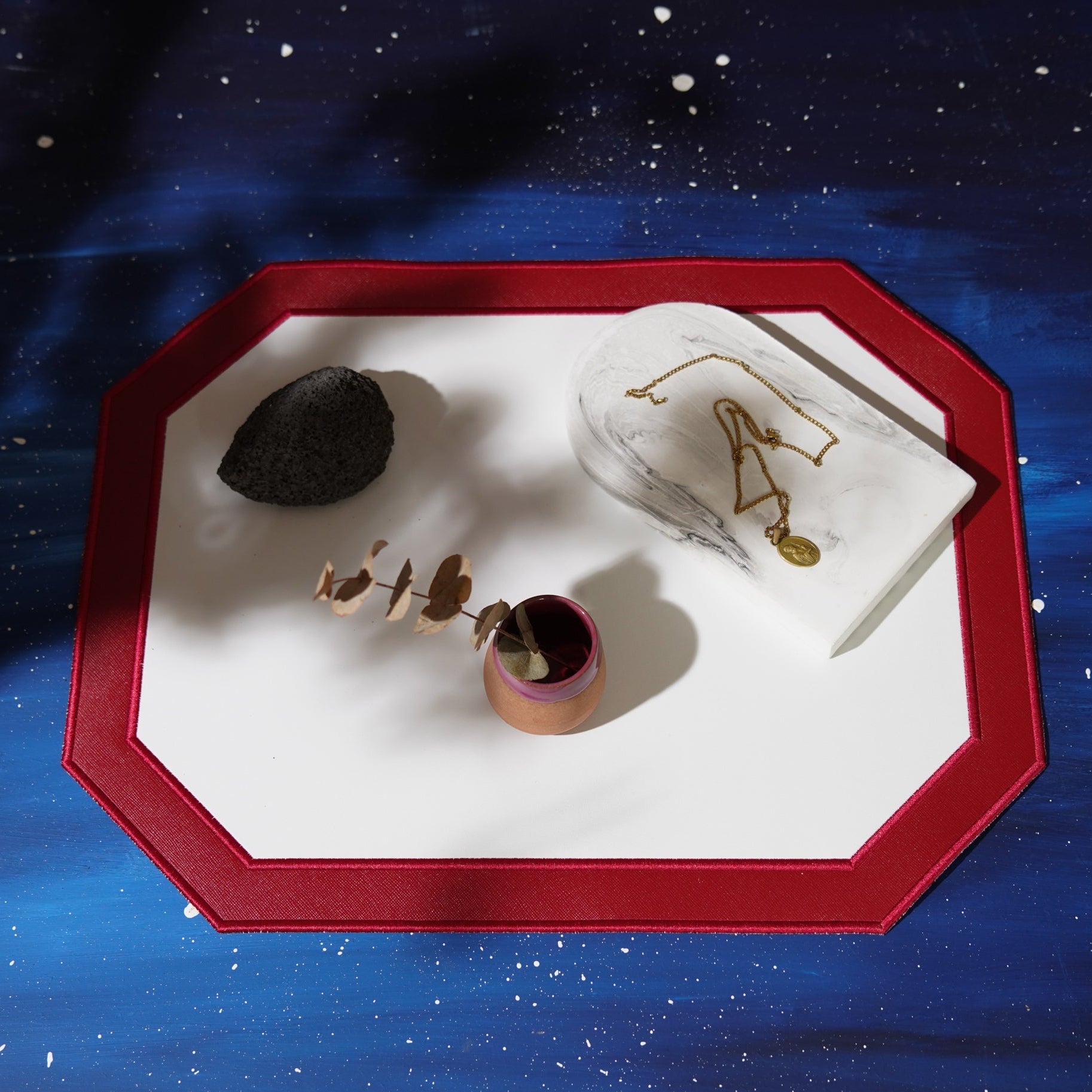 Decorative tray with a rock, plant, and decorative item against a starry night sky background