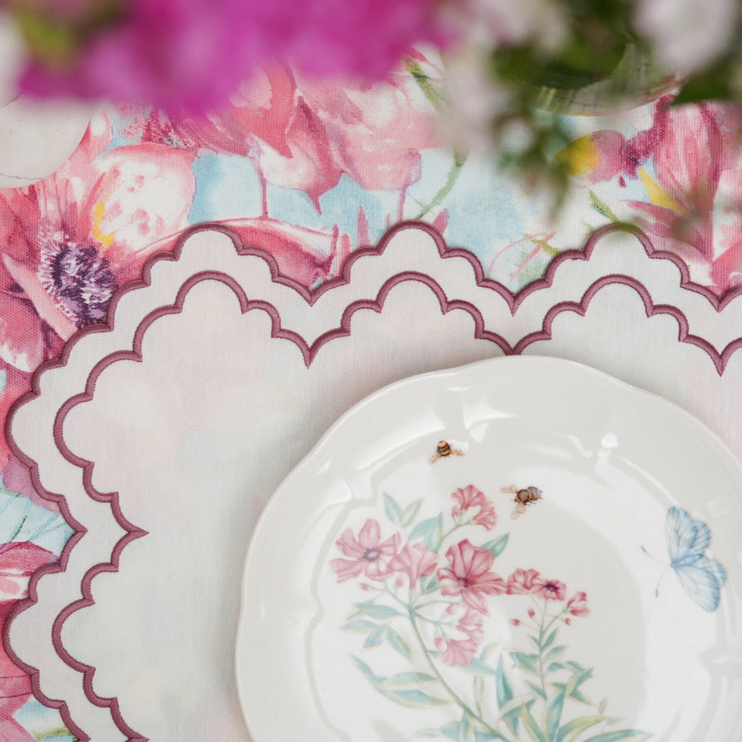 Floral table setting with plates and cutlery on a colorful tablecloth.