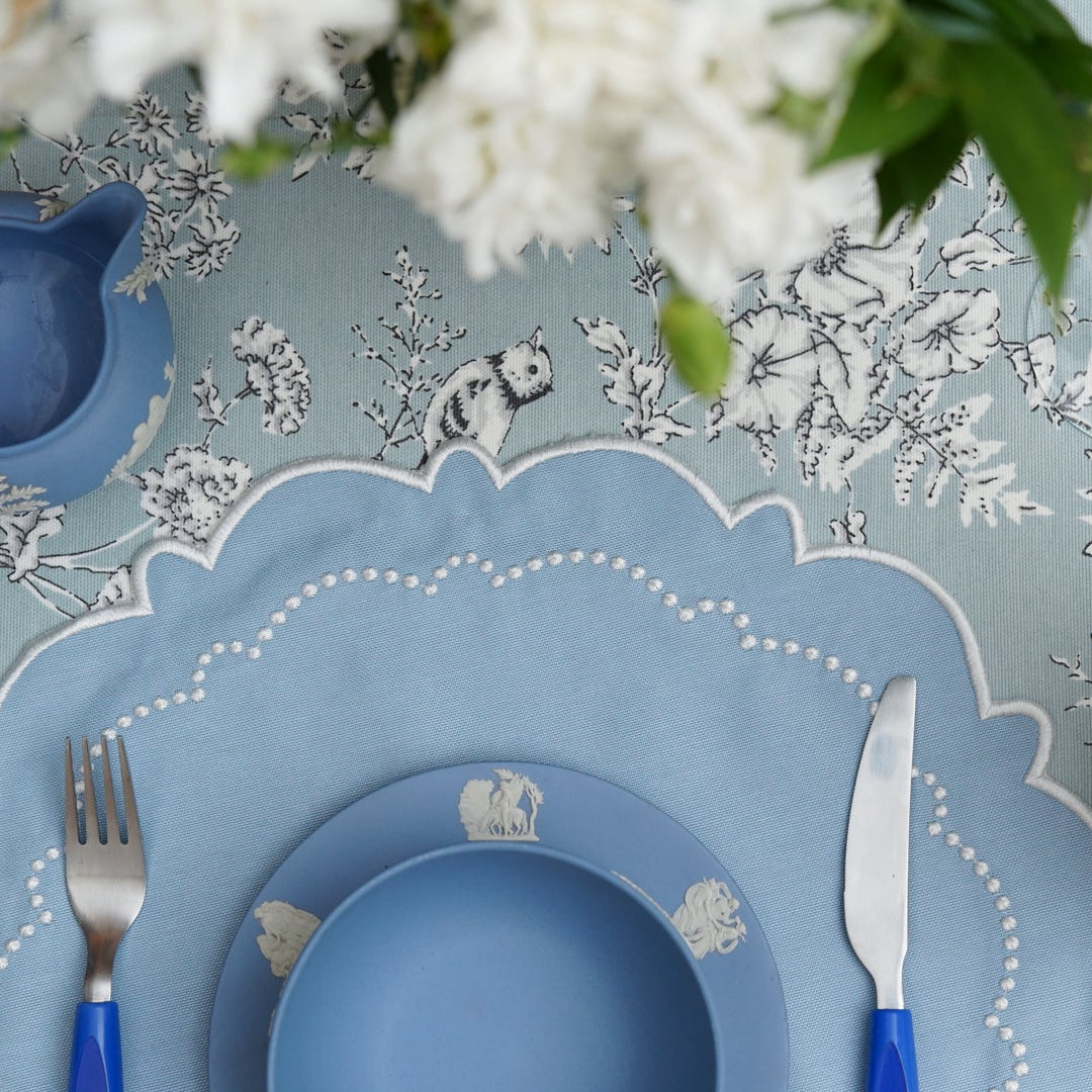 Detailed table setting with blue plates, cutlery, and floral decorations.
