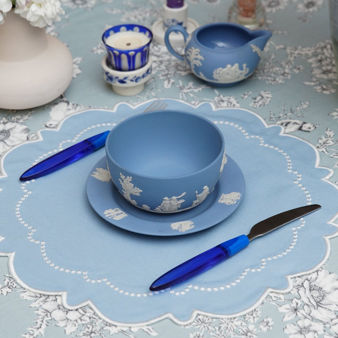 Blue ceramic cup and saucer on a decorative table setting.