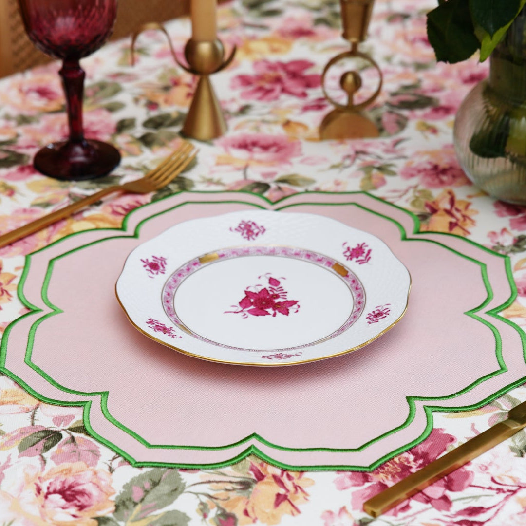 Elegant table setting with floral tablecloth and pink placemat.
