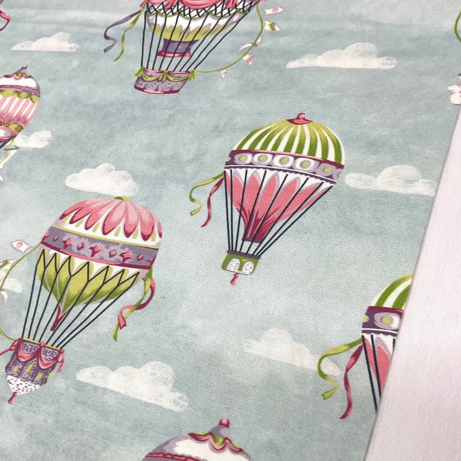 A rectangular tablecloth with a cotton-blend fabric featuring a pattern of illustrated hot air balloons in multicolored hues on a light background.