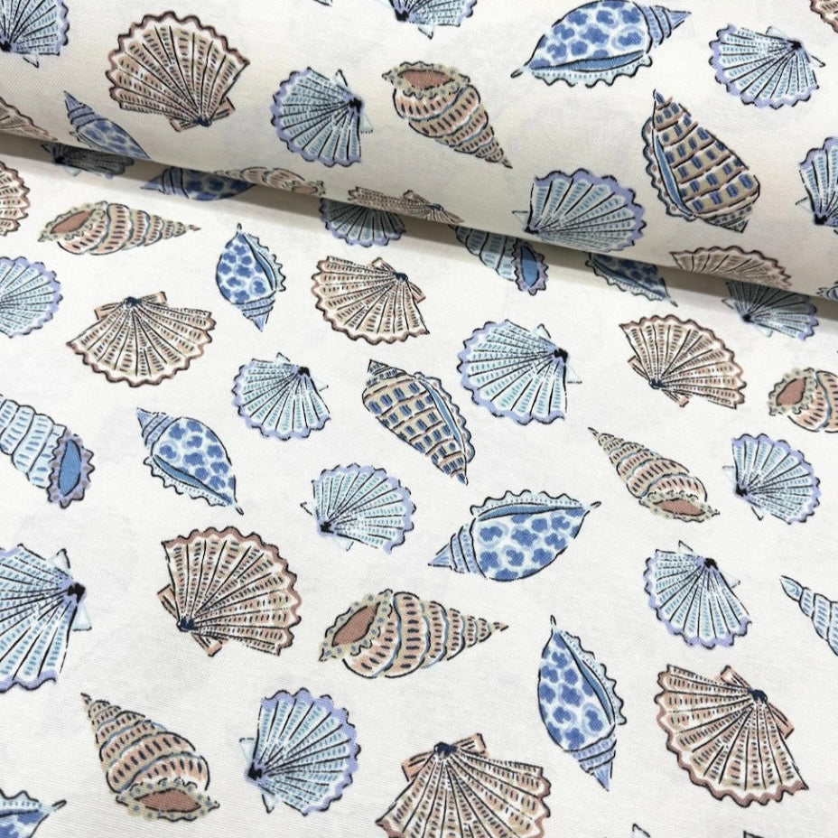 A rectangular tablecloth with a blue and white shell pattern, displayed in a rolled fashion.