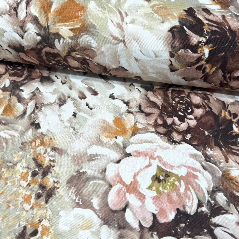 Close-up view of a floral rectangle tablecloth with a variety of colors including white, brown, and pink.
