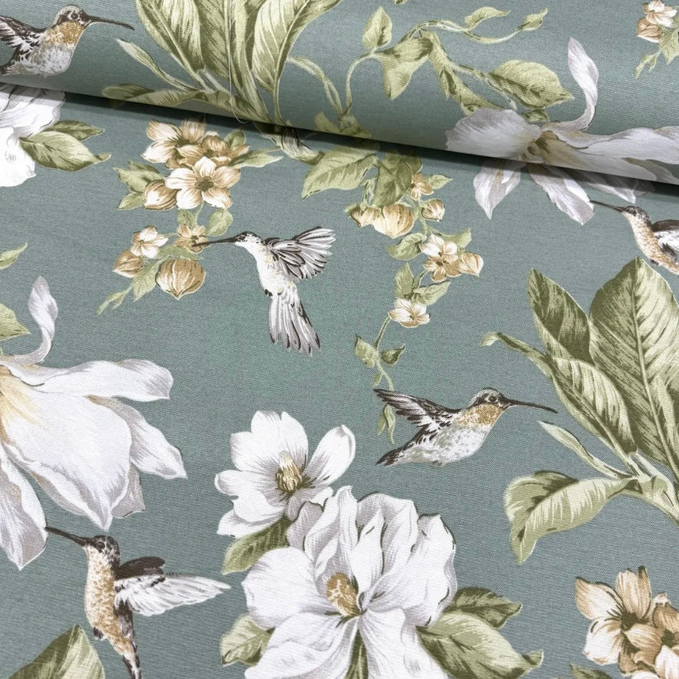 A tablecloth featuring a floral pattern with hummingbirds, flowers, and green leaves on a muted background.
