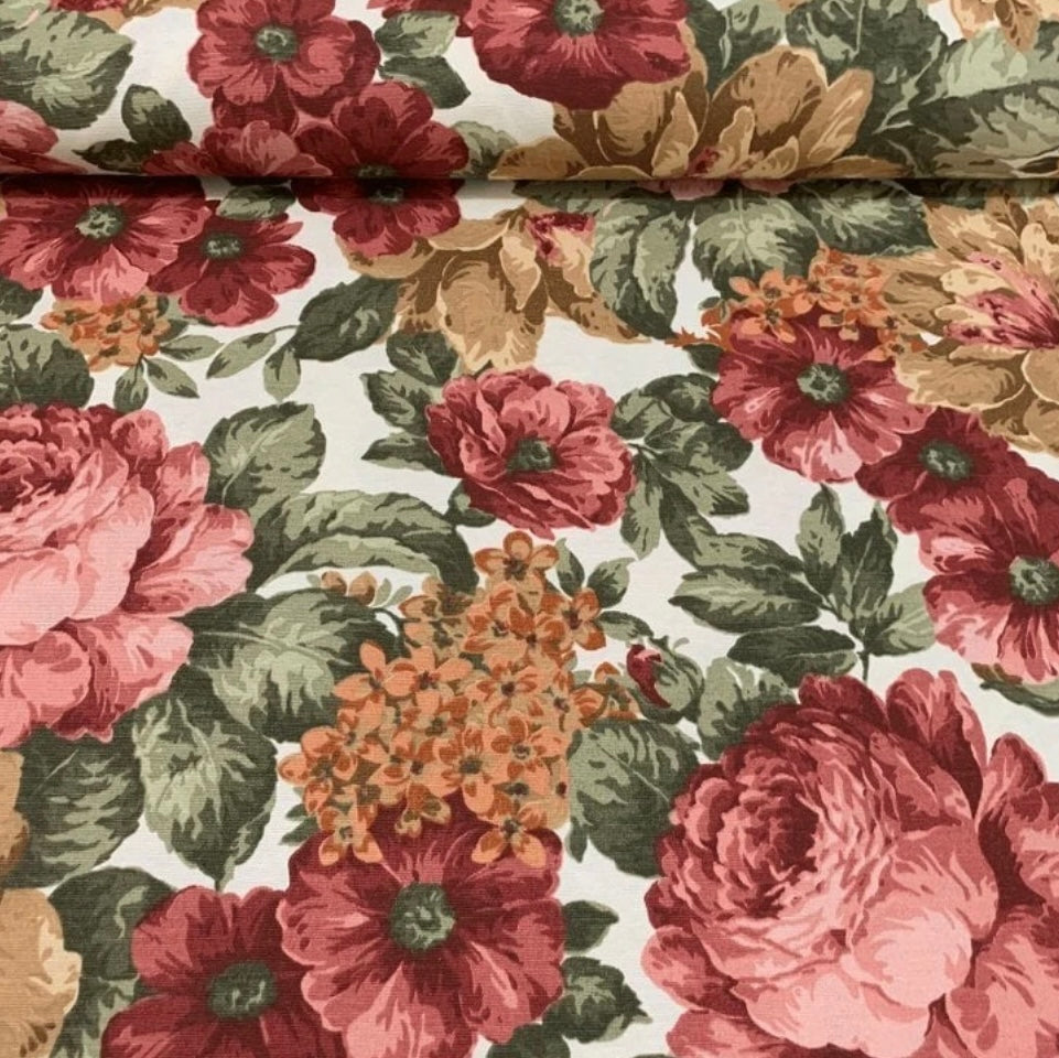 A rectangular tablecloth with a floral pattern featuring various colors such as red, green, and brown on a beige background.