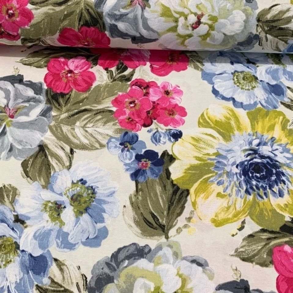 A rectangular tablecloth with a floral pattern in shades of pink, blue, yellow, and green, displayed on a rolled-up state.