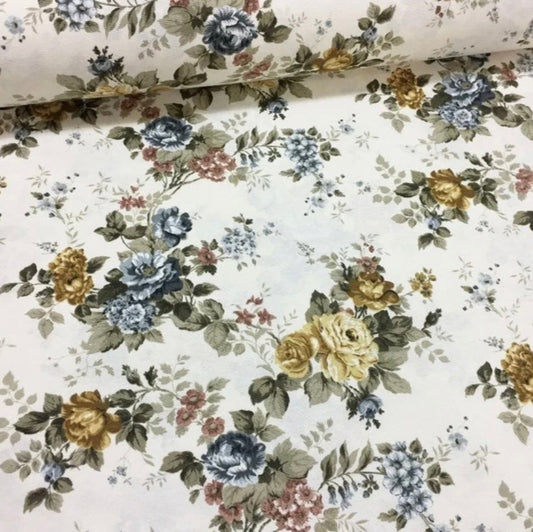 A rolled-up rectangular tablecloth featuring a floral pattern with yellow, blue, and white flowers on a beige background.