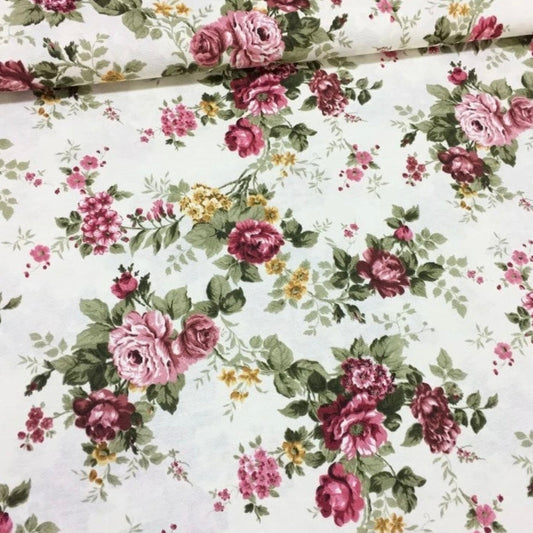 A pink and white rectangle tablecloth with a floral pattern rolled up.