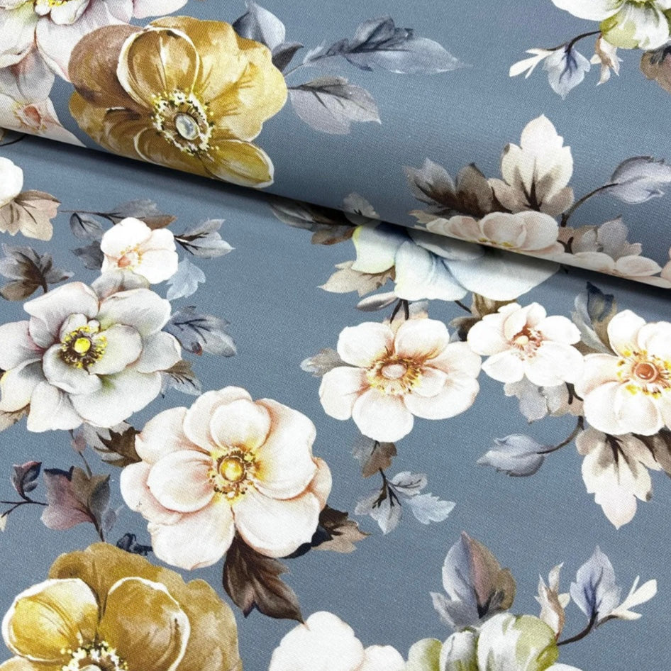 A gray tablecloth with a floral pattern featuring white and yellow flowers and green leaves.