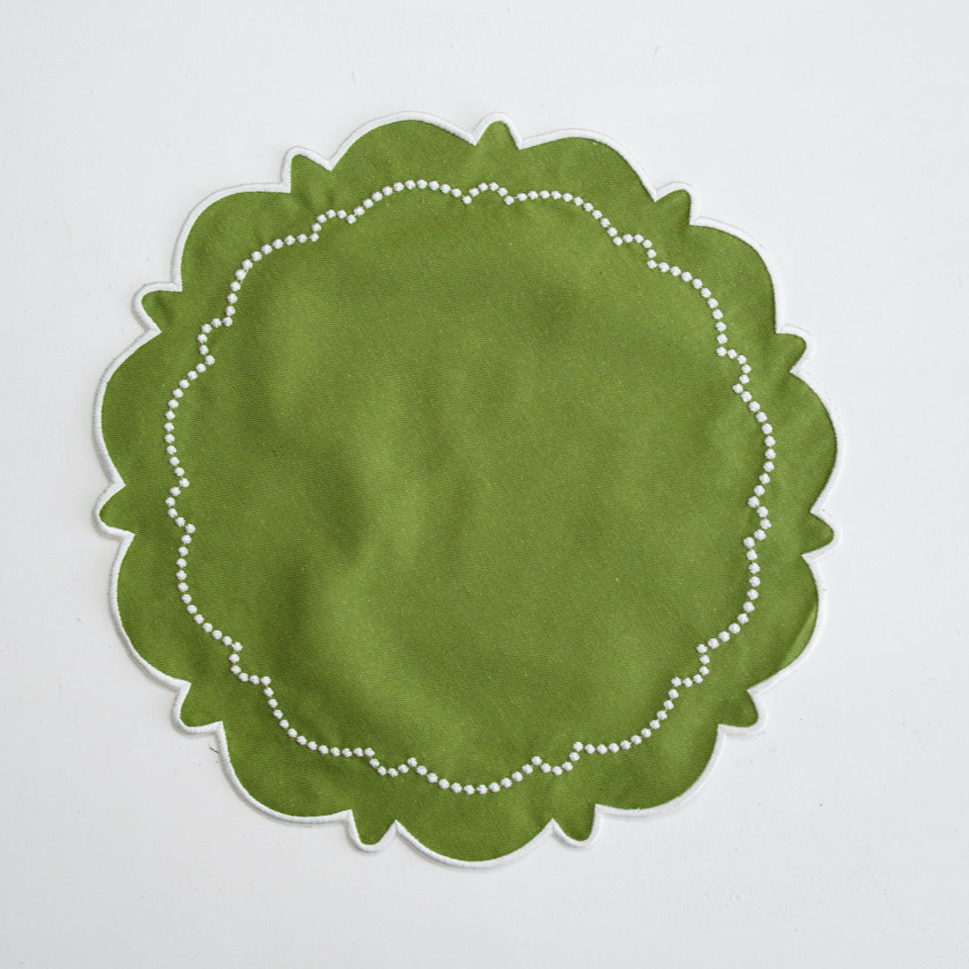 Green round placemat with white scalloped edge on a light gray background