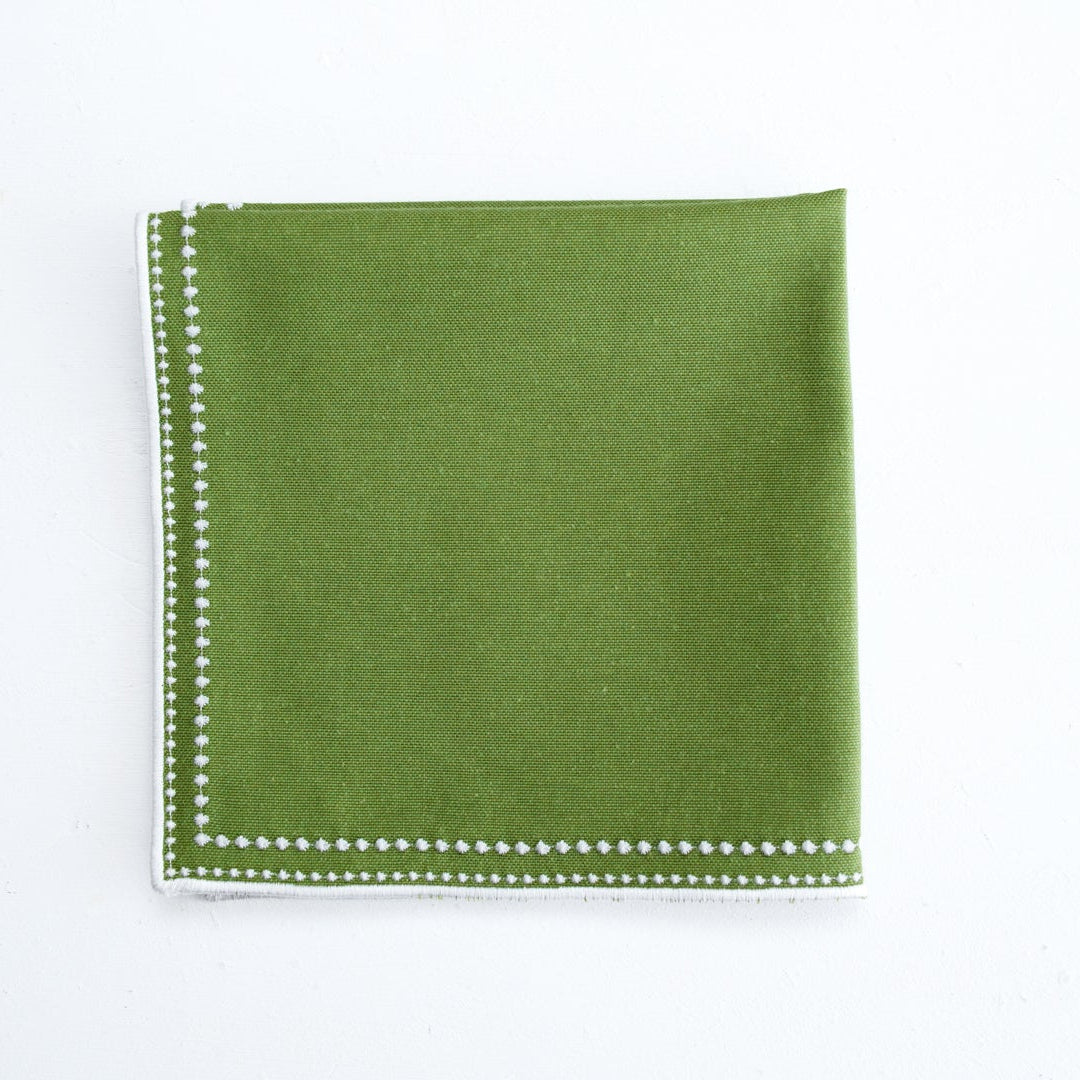 Green napkin with white trim on a white background