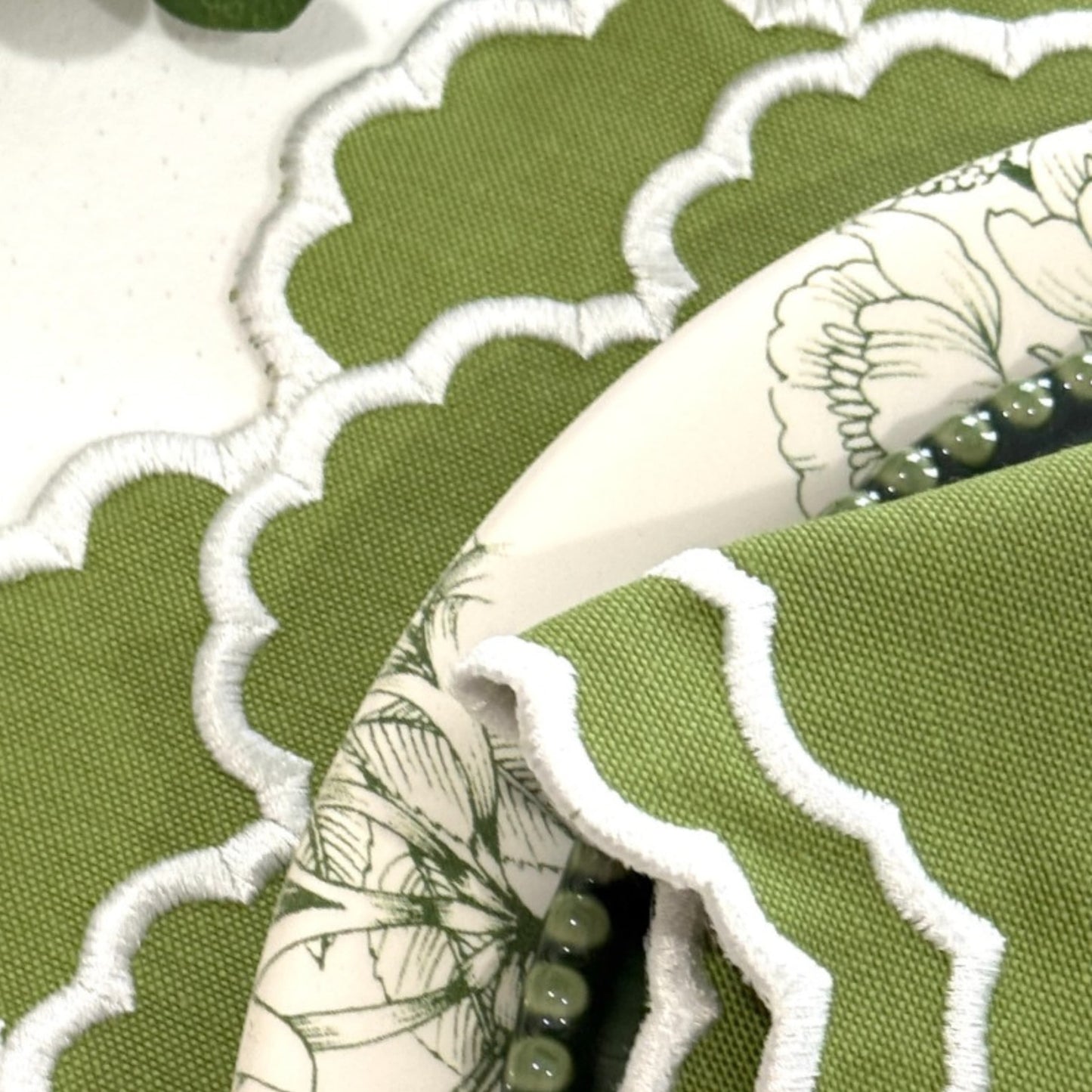 Close-up of green fabric with scalloped edge and floral pattern.