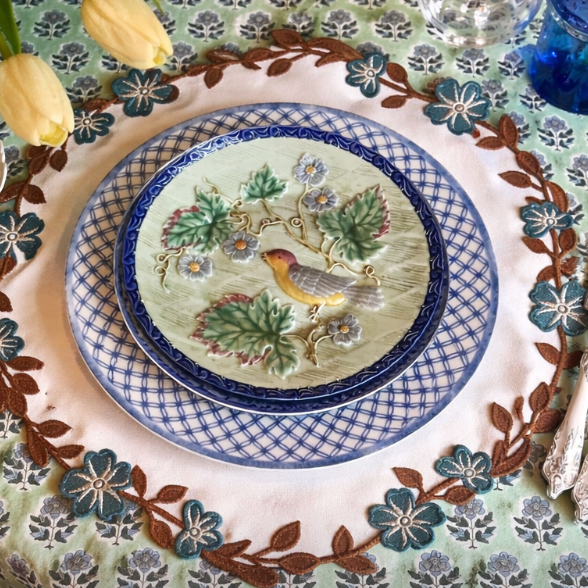 Decorative table setting with a plate featuring a bird design on a patterned tablecloth.