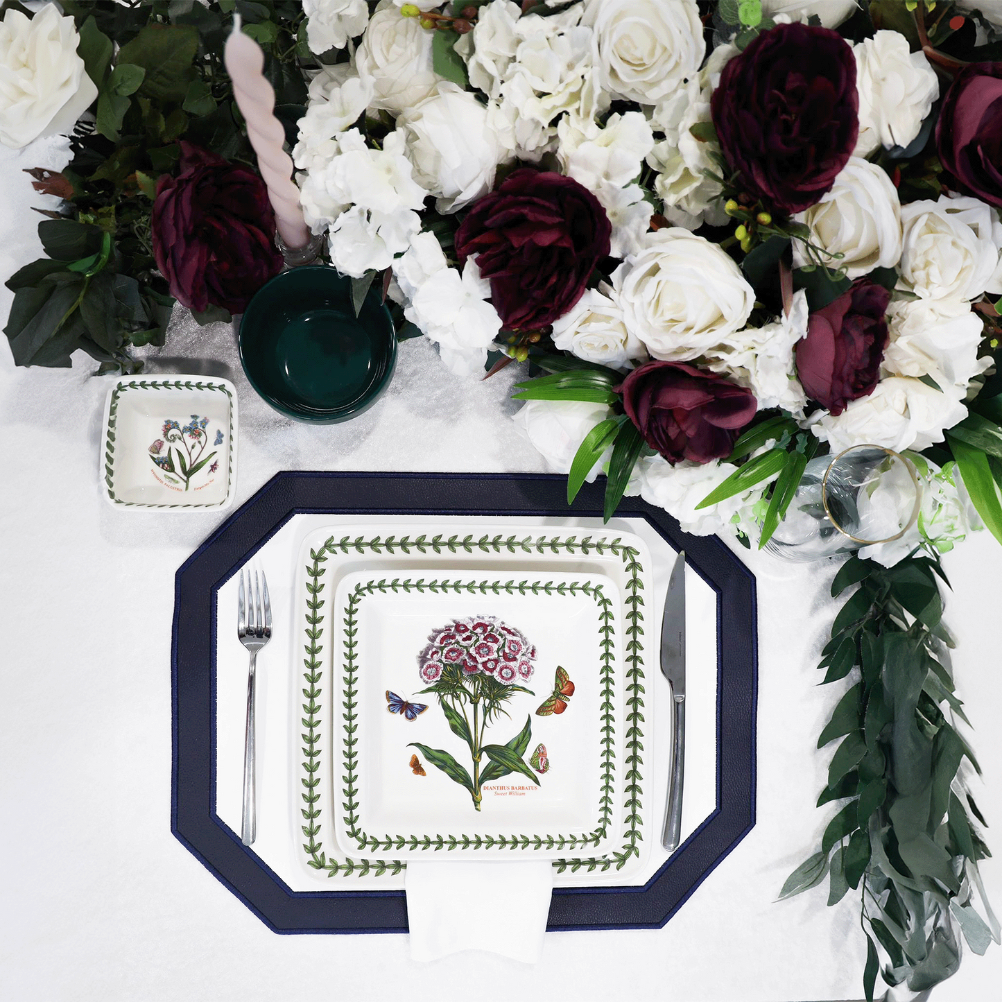 Decorative plate with floral design on a white surface with flowers and candles.