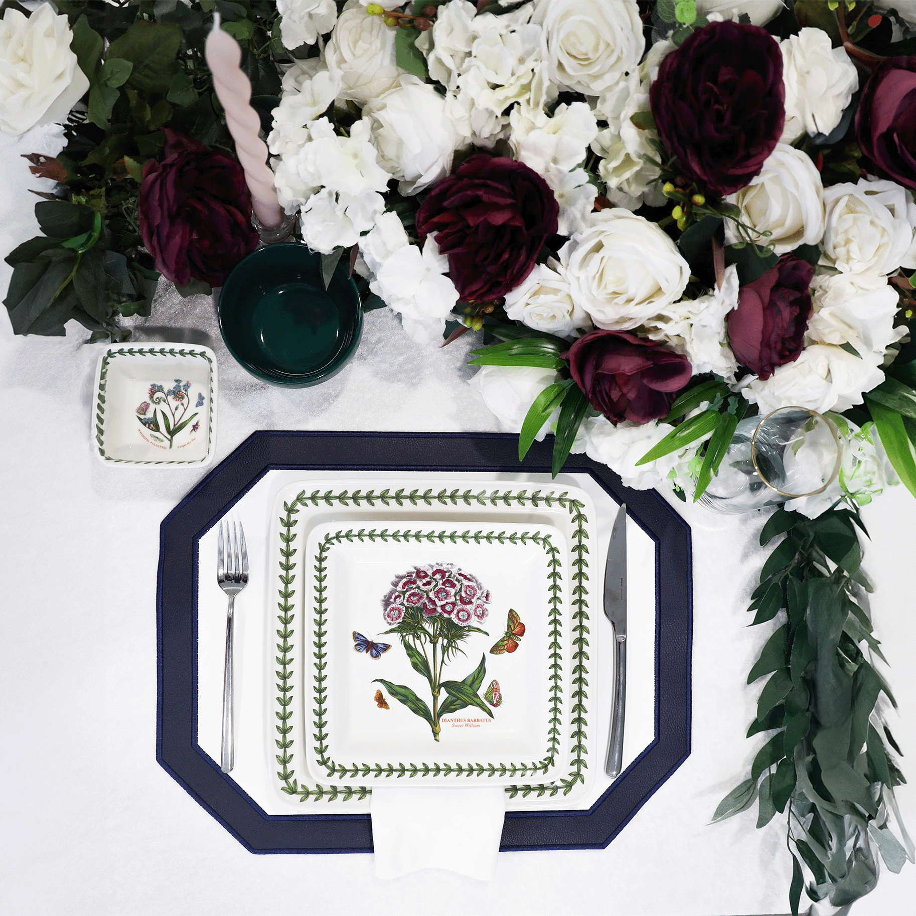 Decorative plate with floral design on a white surface with flowers and candles.