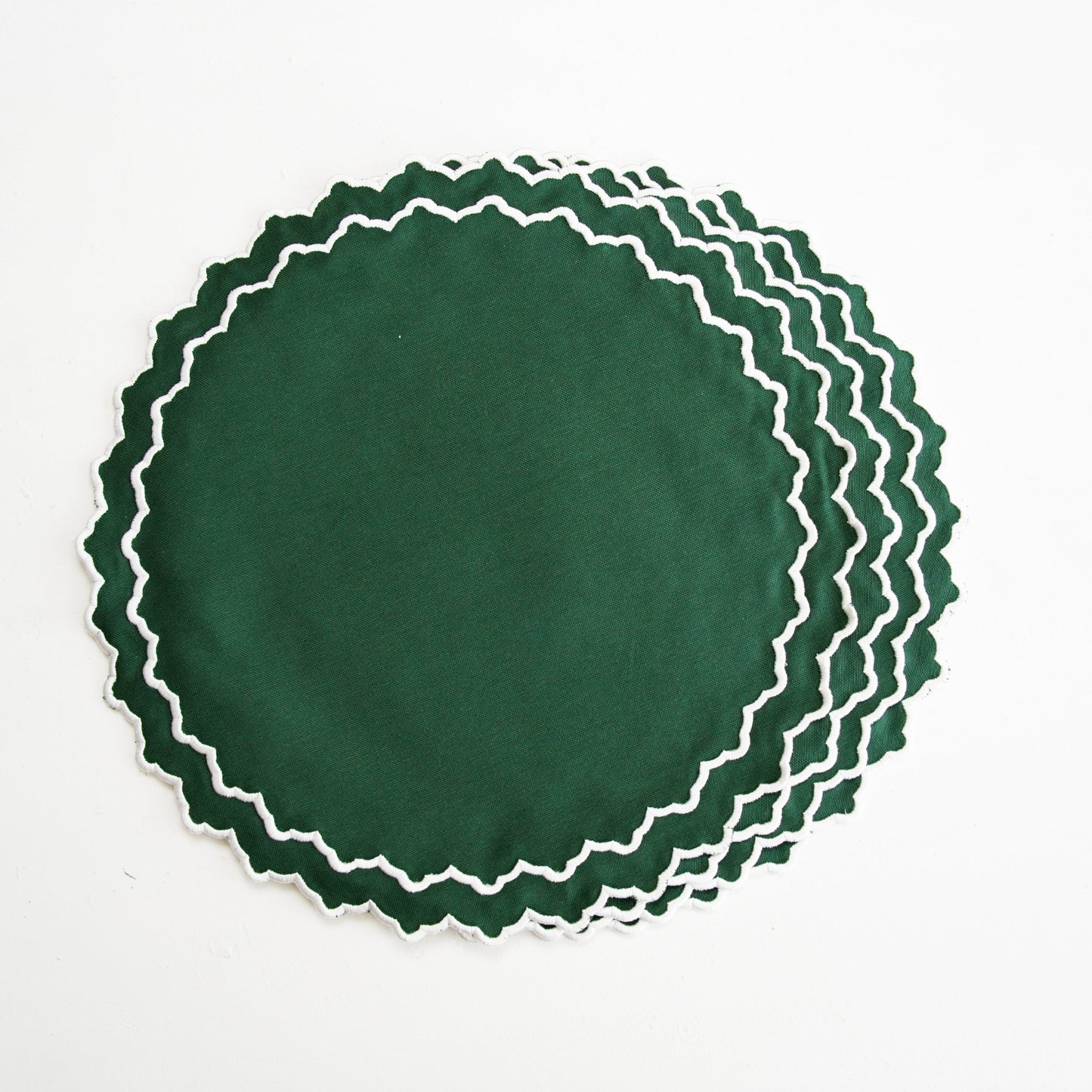 Set of green placemats with white scalloped edges on a white background