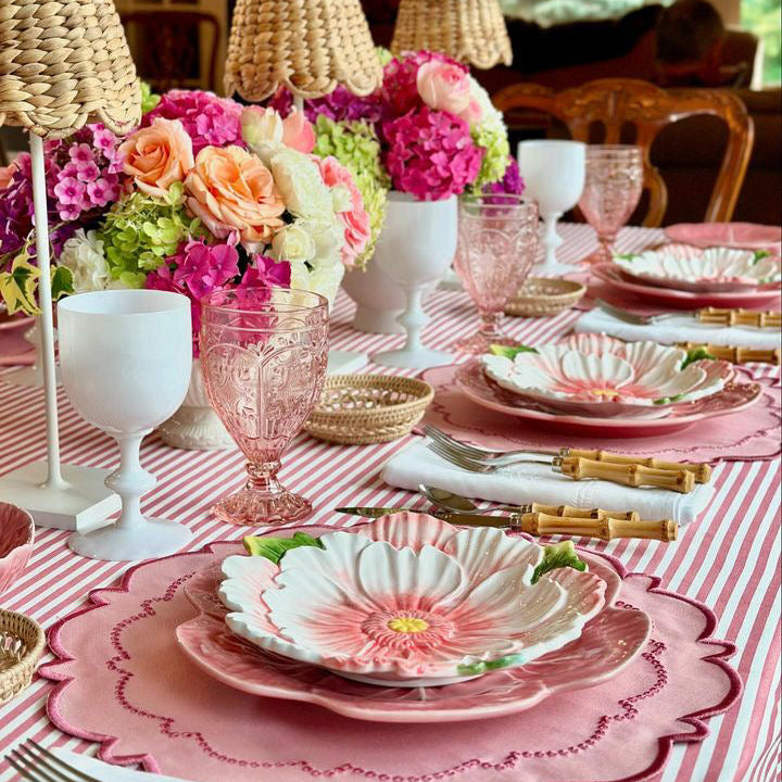 Elegant table setting with floral centerpieces and pink tablecloth.