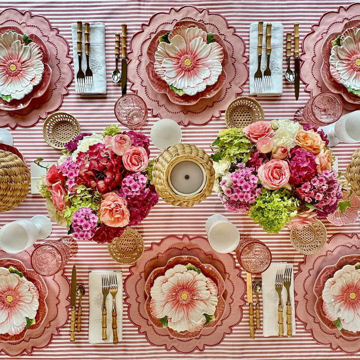 Decorative table setting with floral centerpieces, plates, and cutlery on a pink and white checkered tablecloth.