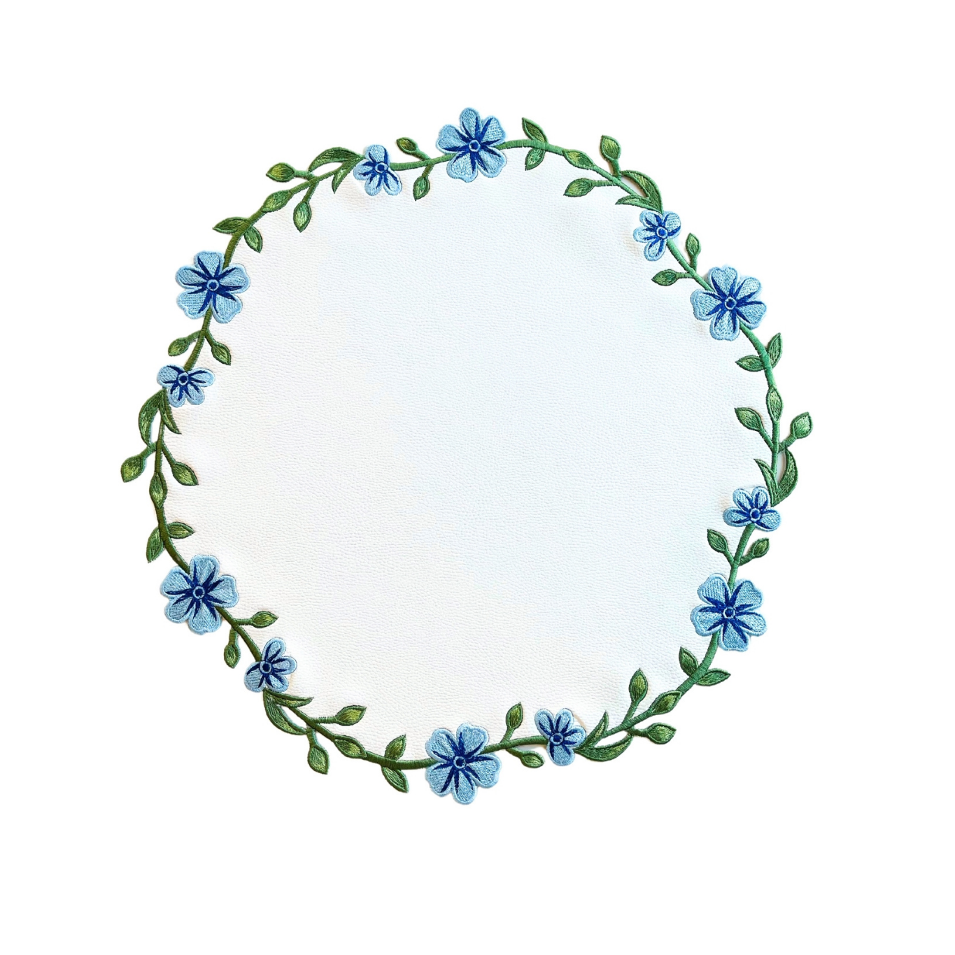 A round white faux leather placemat with blue floral embroidery around the edge.
