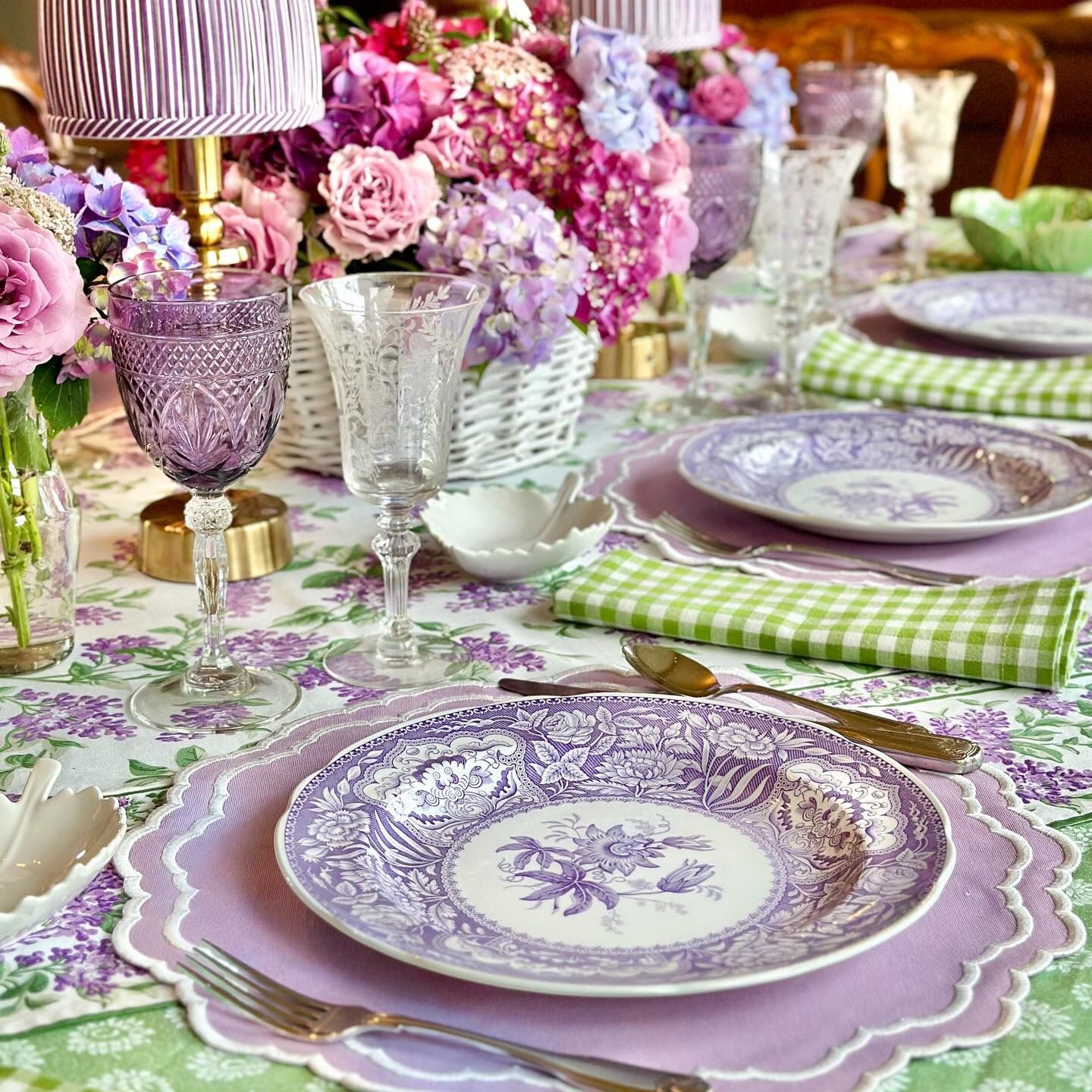 Elegant table setting with purple and green accents, including plates, glasses, and napkins.