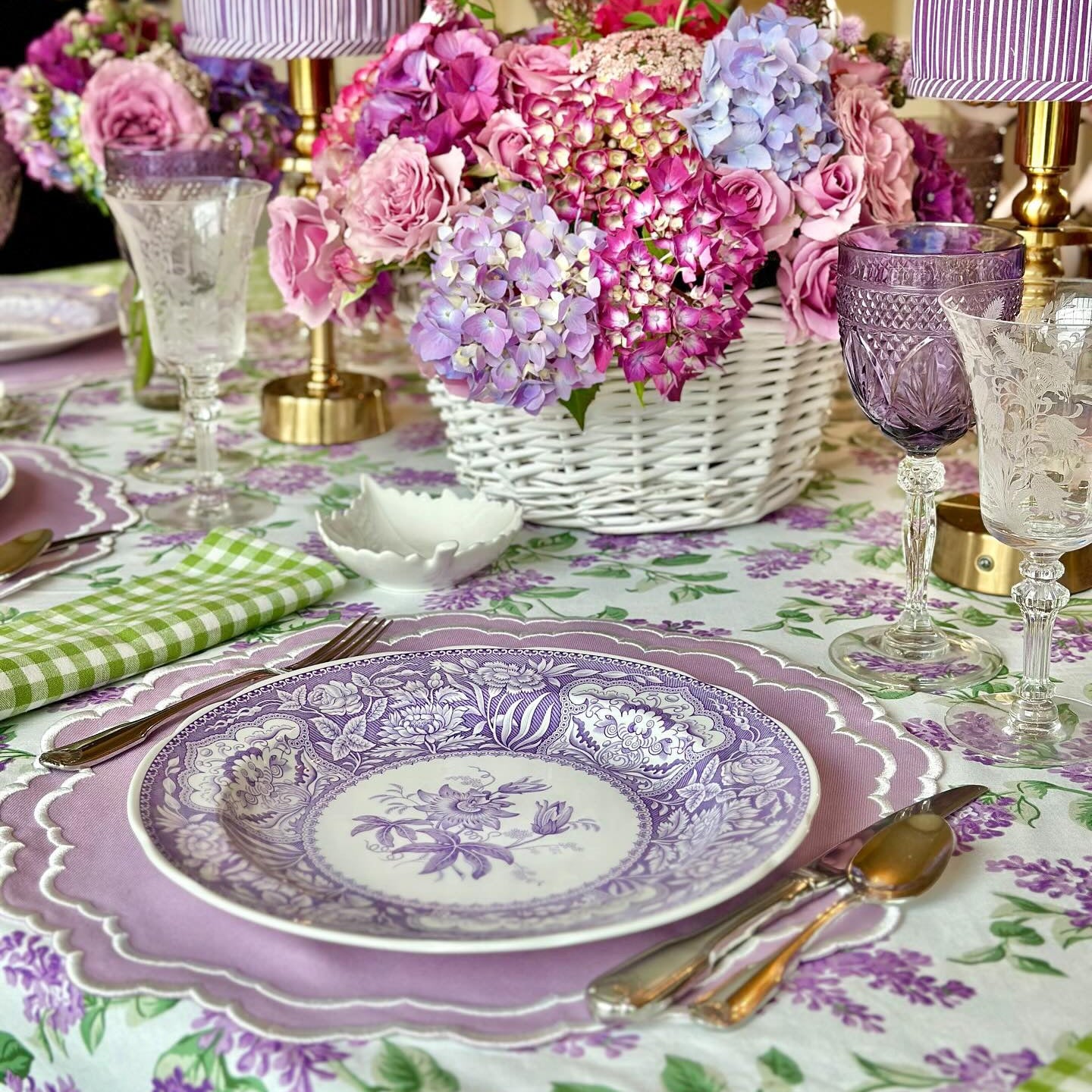 Decorative table setting with floral centerpiece, plates, and glasses on a floral tablecloth.
