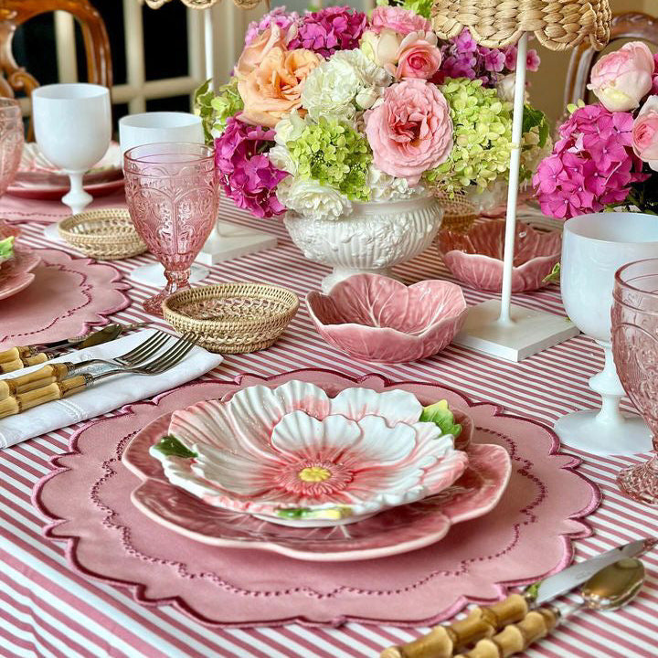 Elegant table setting with pink tablecloth, floral centerpieces, and decorative plates.