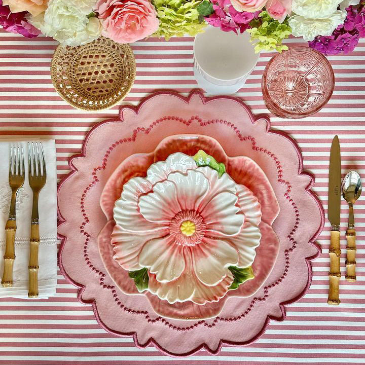 Decorative table setting with floral centerpiece, striped tablecloth, and pink plates.