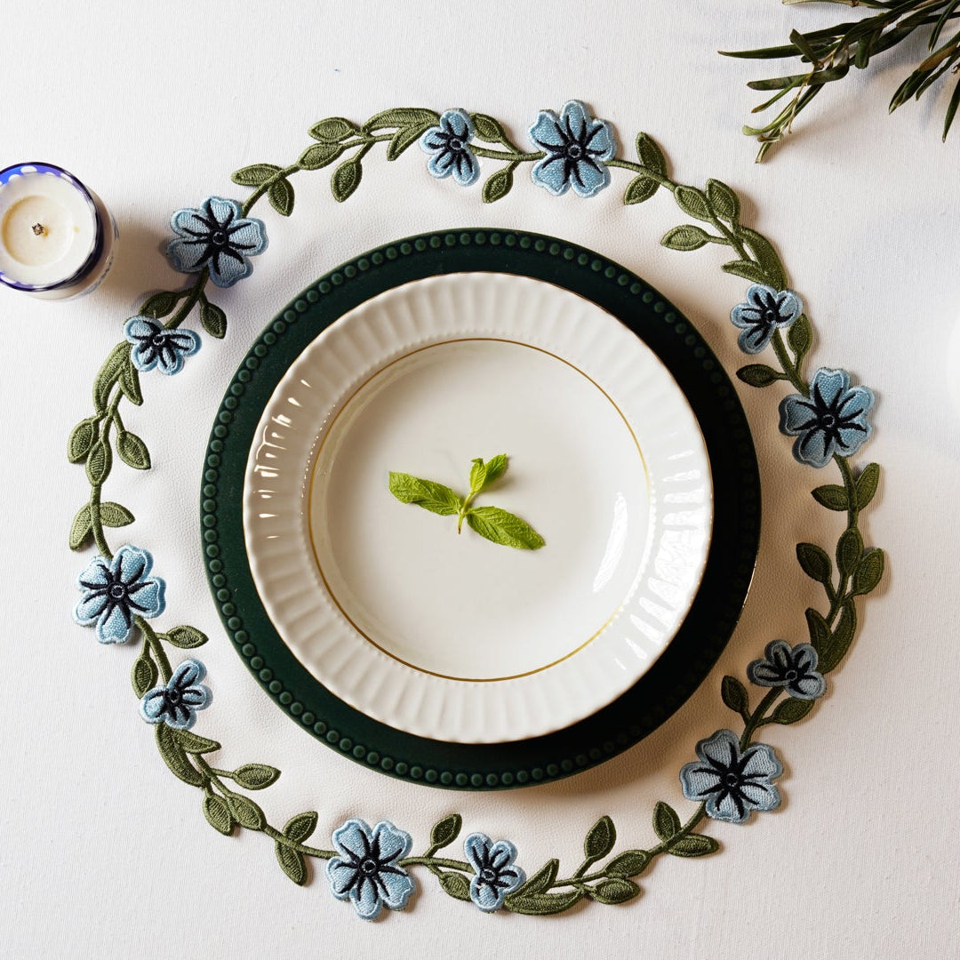 Table setting with plates, flowers, and a cup on a white surface