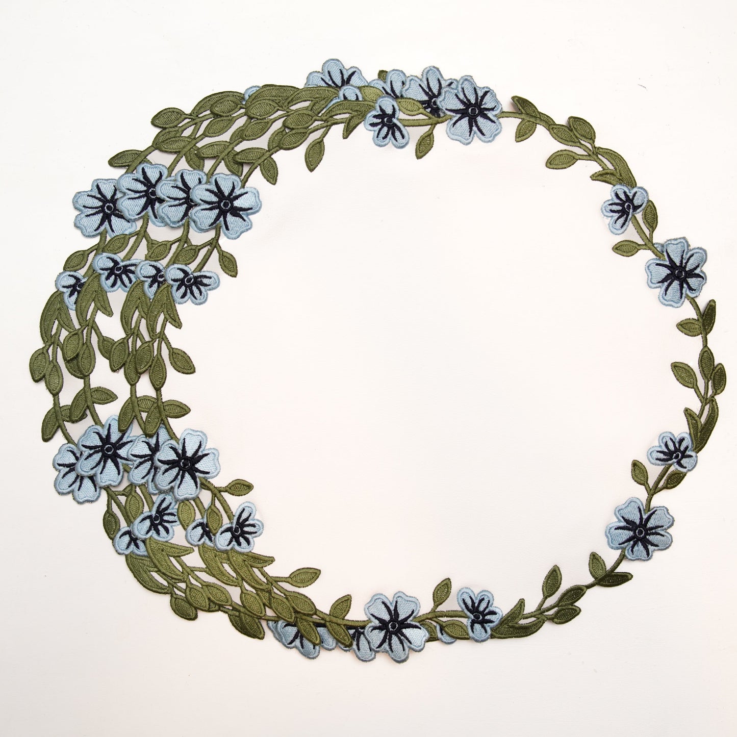 Floral wreath with blue flowers and green leaves on a white background