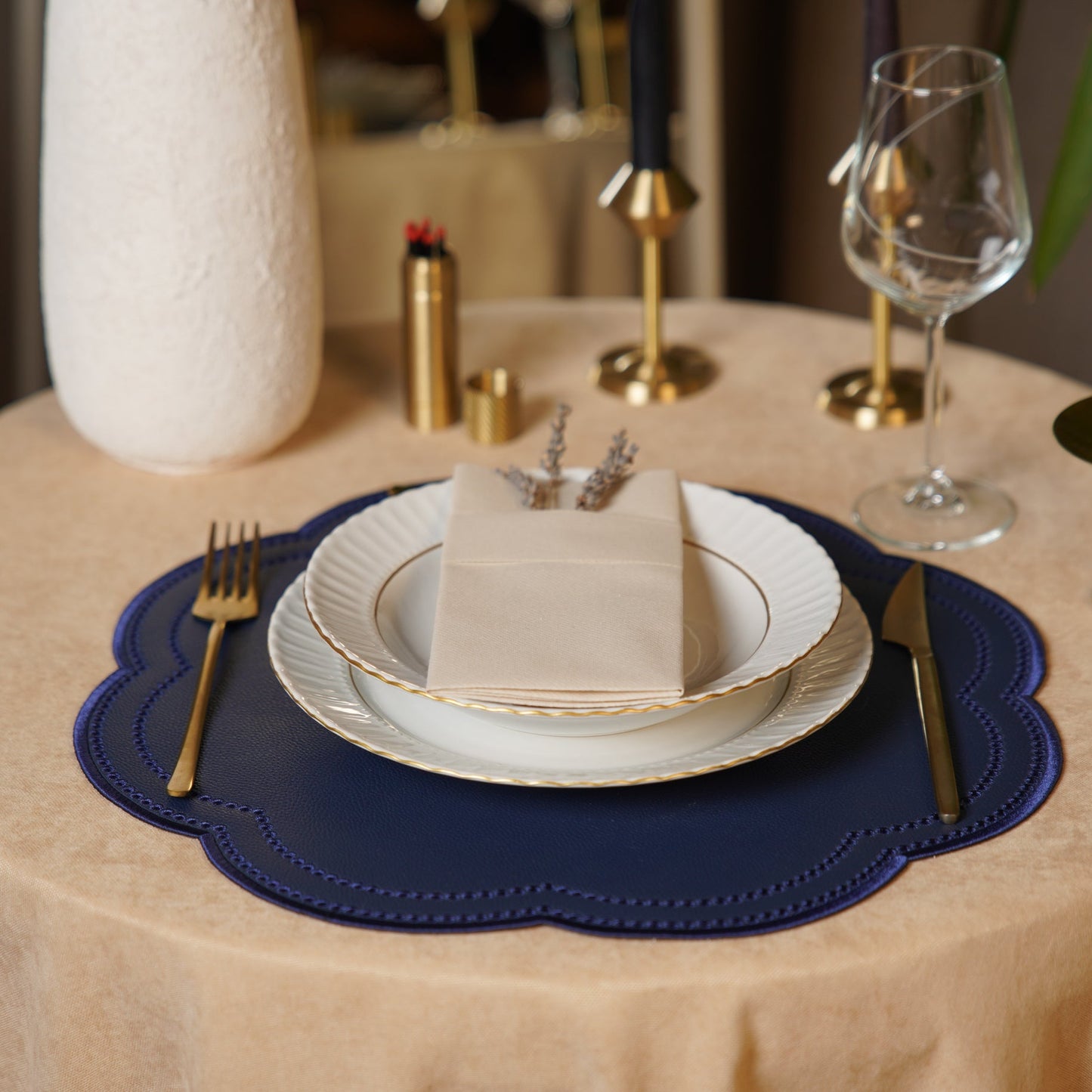 Dining table setting with plates, cutlery, and a small cake on a blue placemat.
