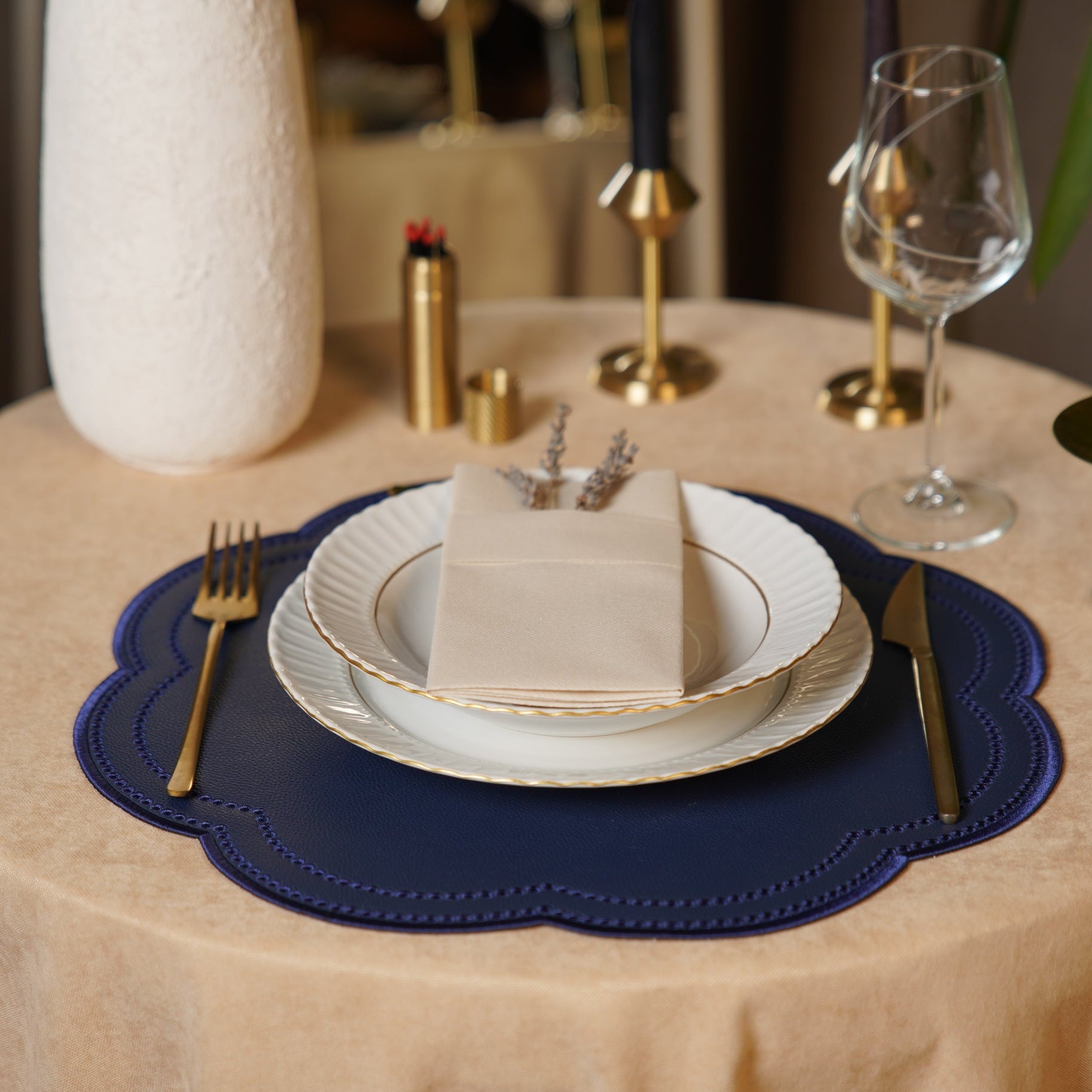Dining table setting with plates, cutlery, and a small cake on a blue placemat.