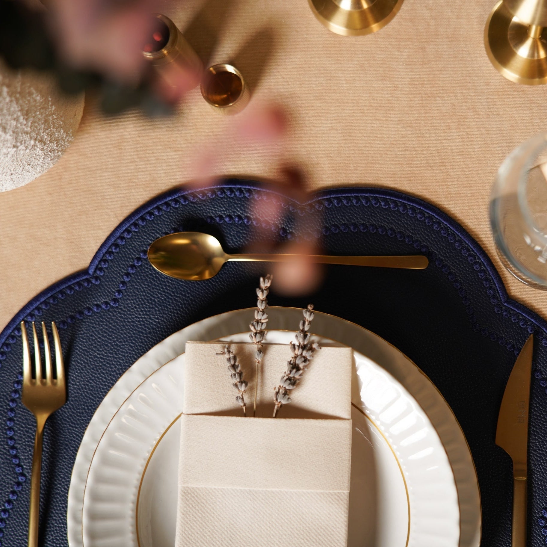 Close-up of a table setting with gold cutlery, white plates, and a blue placemat.