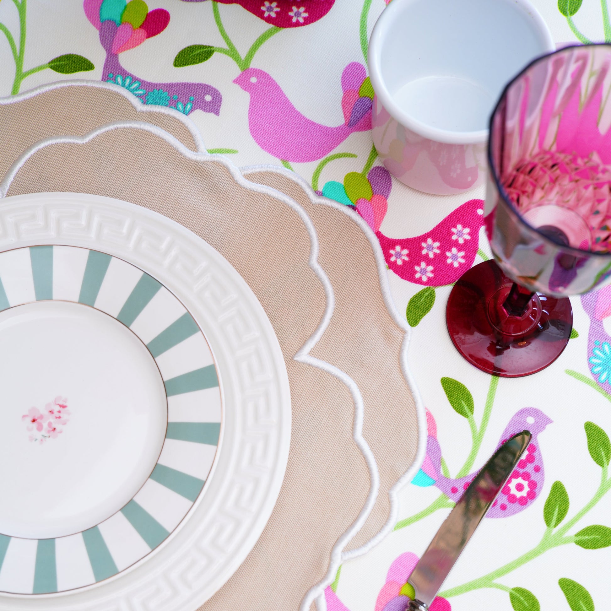 Colorful table setting with a floral placemat, plates, and cutlery.