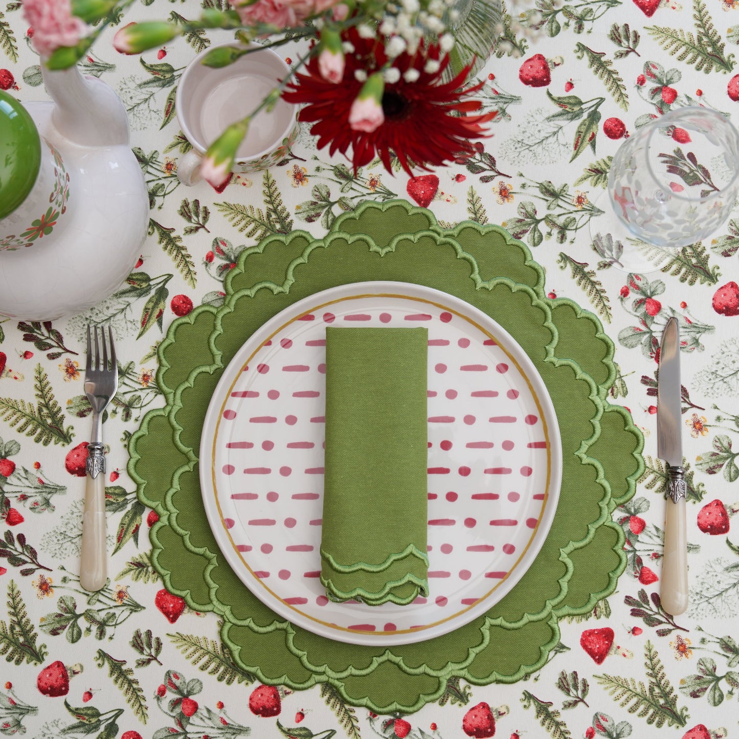 Decorative table setting with a green letter 'I' on a floral patterned tablecloth.