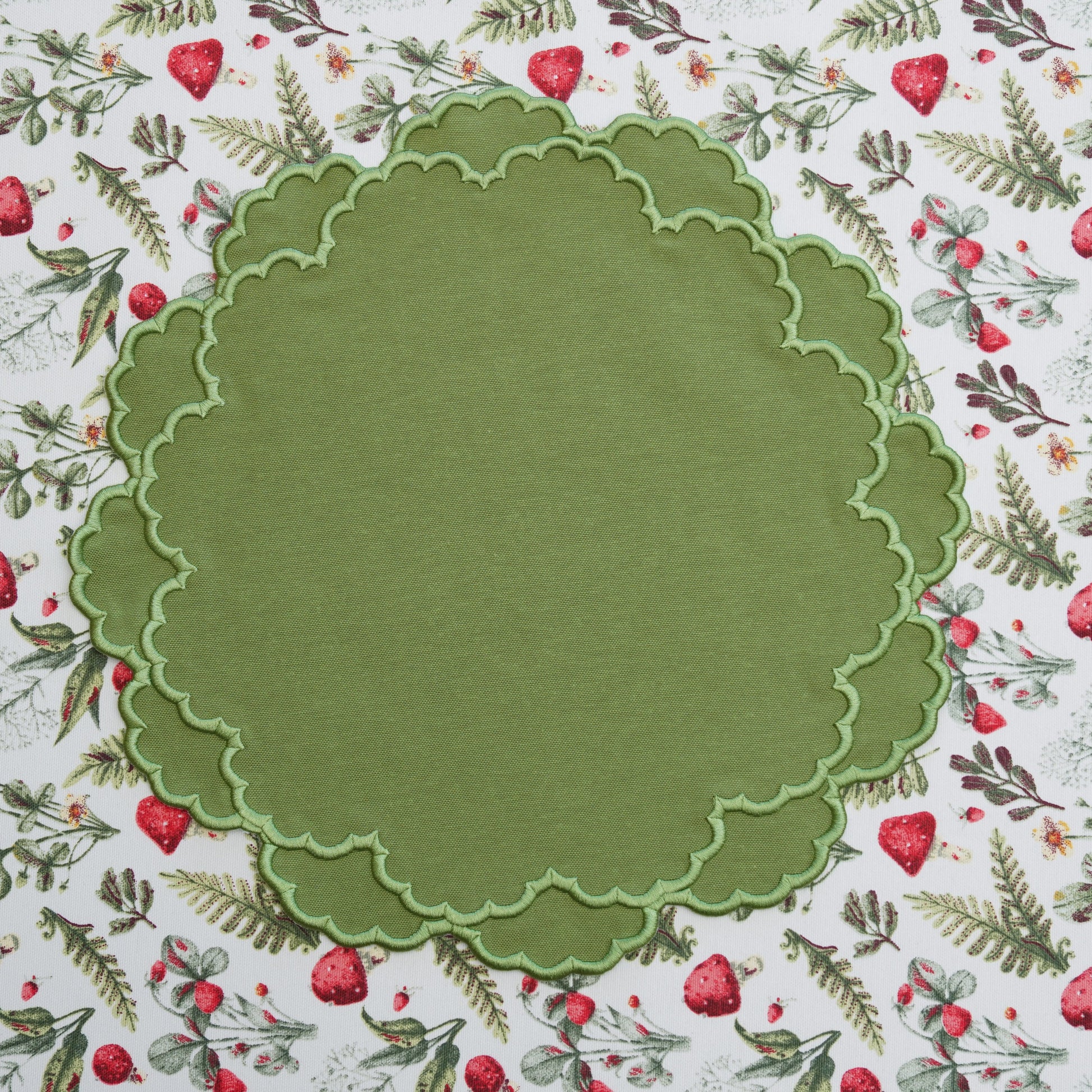 Green scalloped-edge circle on a patterned background with red berries and green leaves.