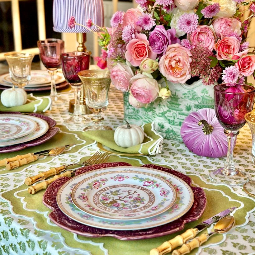 Decorative table setting with floral centerpiece, colorful plates, and glasses.