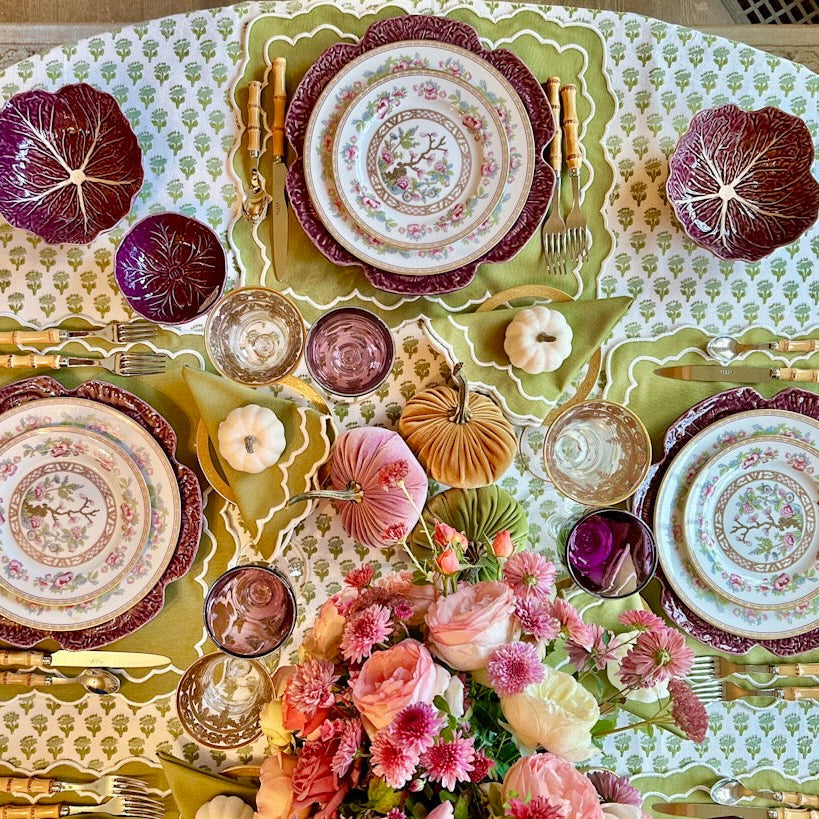 Decorative table setting with floral centerpiece, plates, and cutlery on a patterned tablecloth.