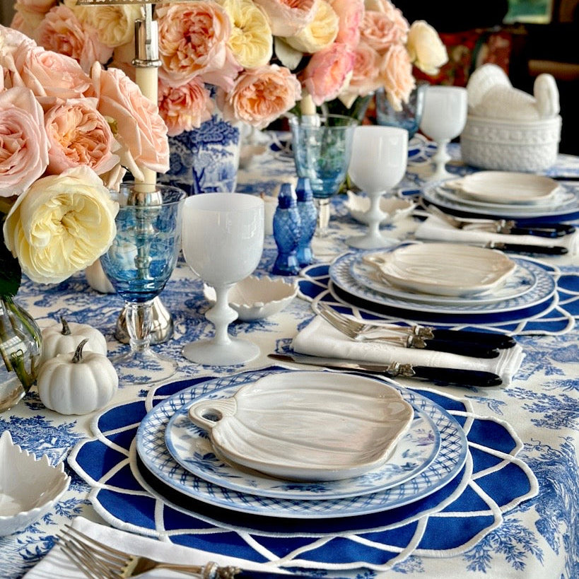 Elegant table setting with blue and white plates, floral centerpiece, and decorative lamp.