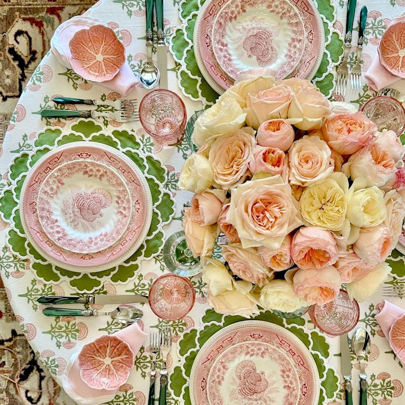 Elegant table setting with floral centerpiece, patterned plates, and cutlery on a decorative tablecloth.