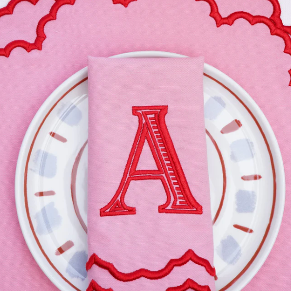 Pink napkin with red letter 'A' on a white plate against a pink background