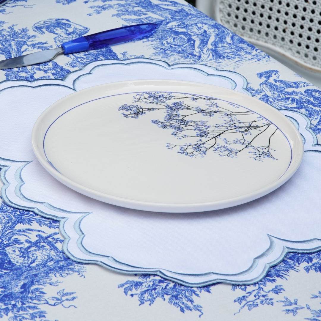 Dining table setting with blue and white patterned tablecloth and plates.